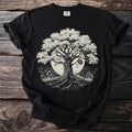 Black t-shirt with a linocut-style tree of life design against a moon and water.