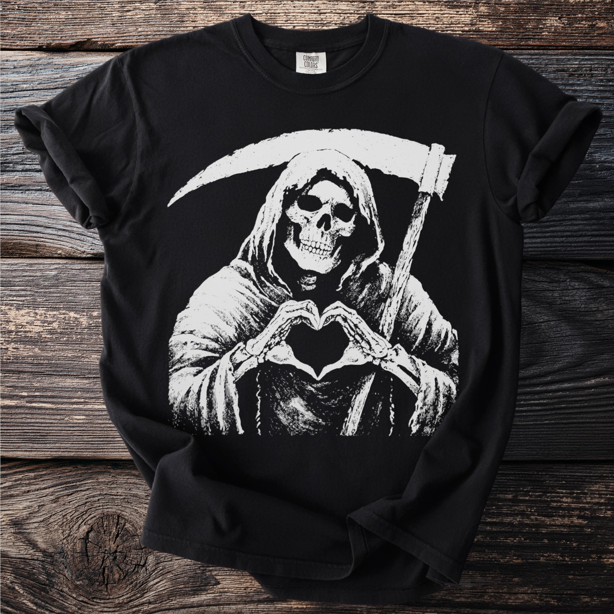 Grim reaper skeleton making a heart shape with bony hands on a black t-shirt.