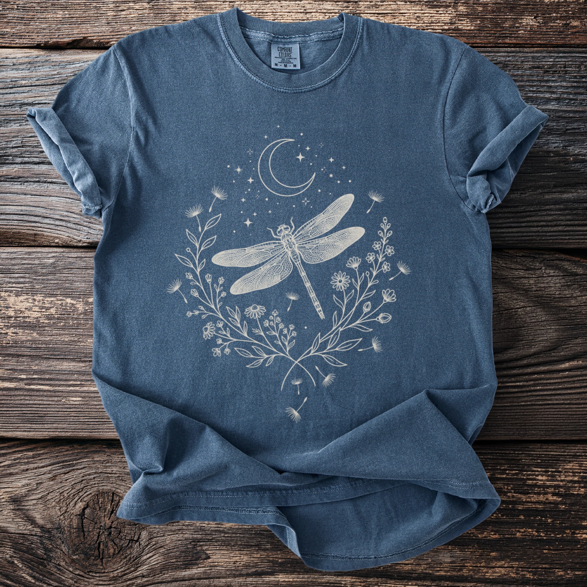 Blue t-shirt with white dragonfly, moon, stars, and floral design.