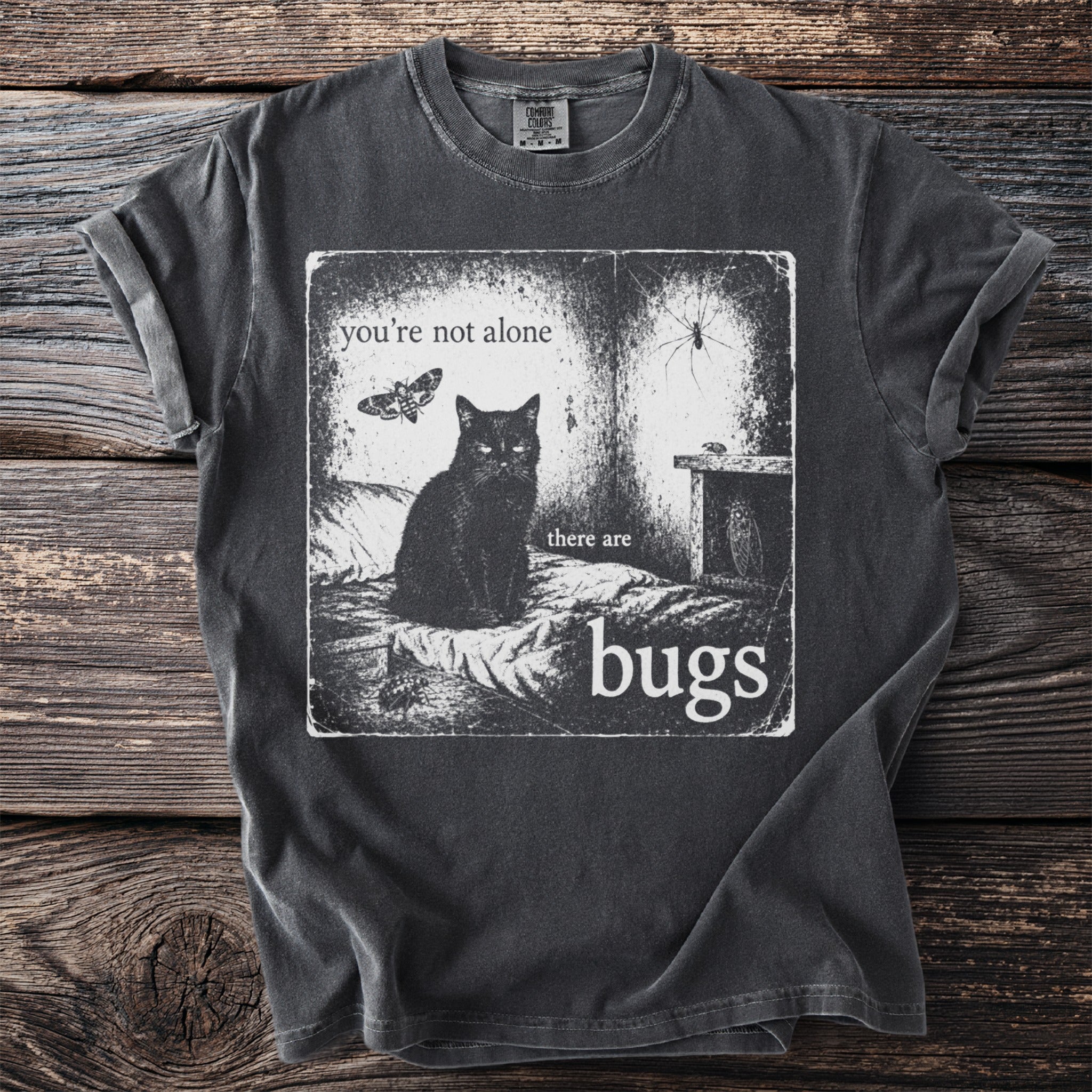 Black t-shirt with graphic of cat, moth, spider, and text "you're not alone there are bugs".