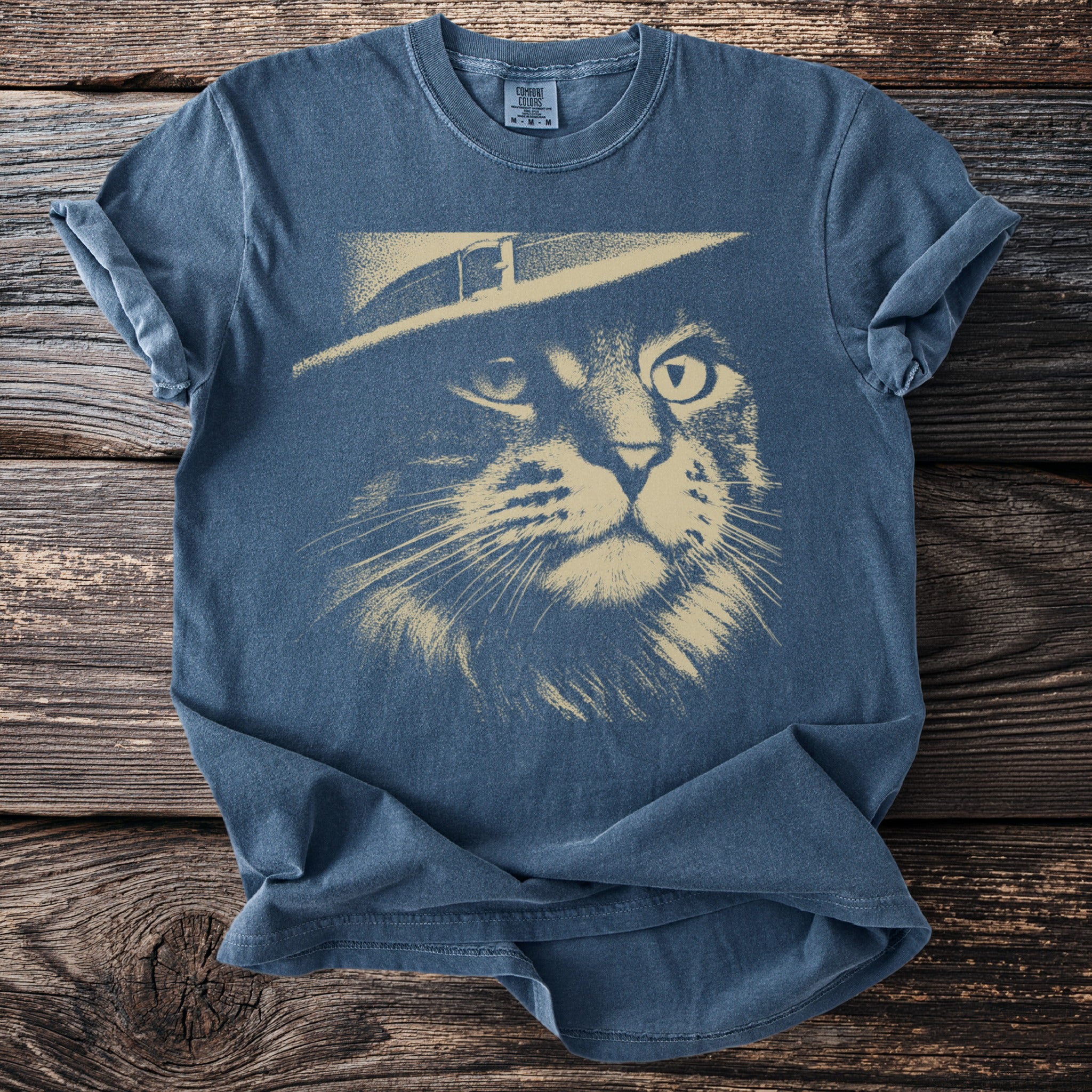 Blue t-shirt with a sketch of a cat's face wearing a hat.