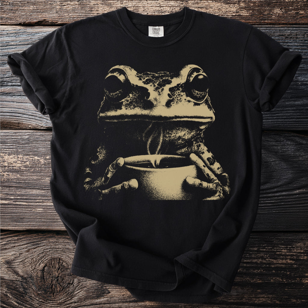 Black t-shirt with a sepia tone print of a frog holding a steaming cup.