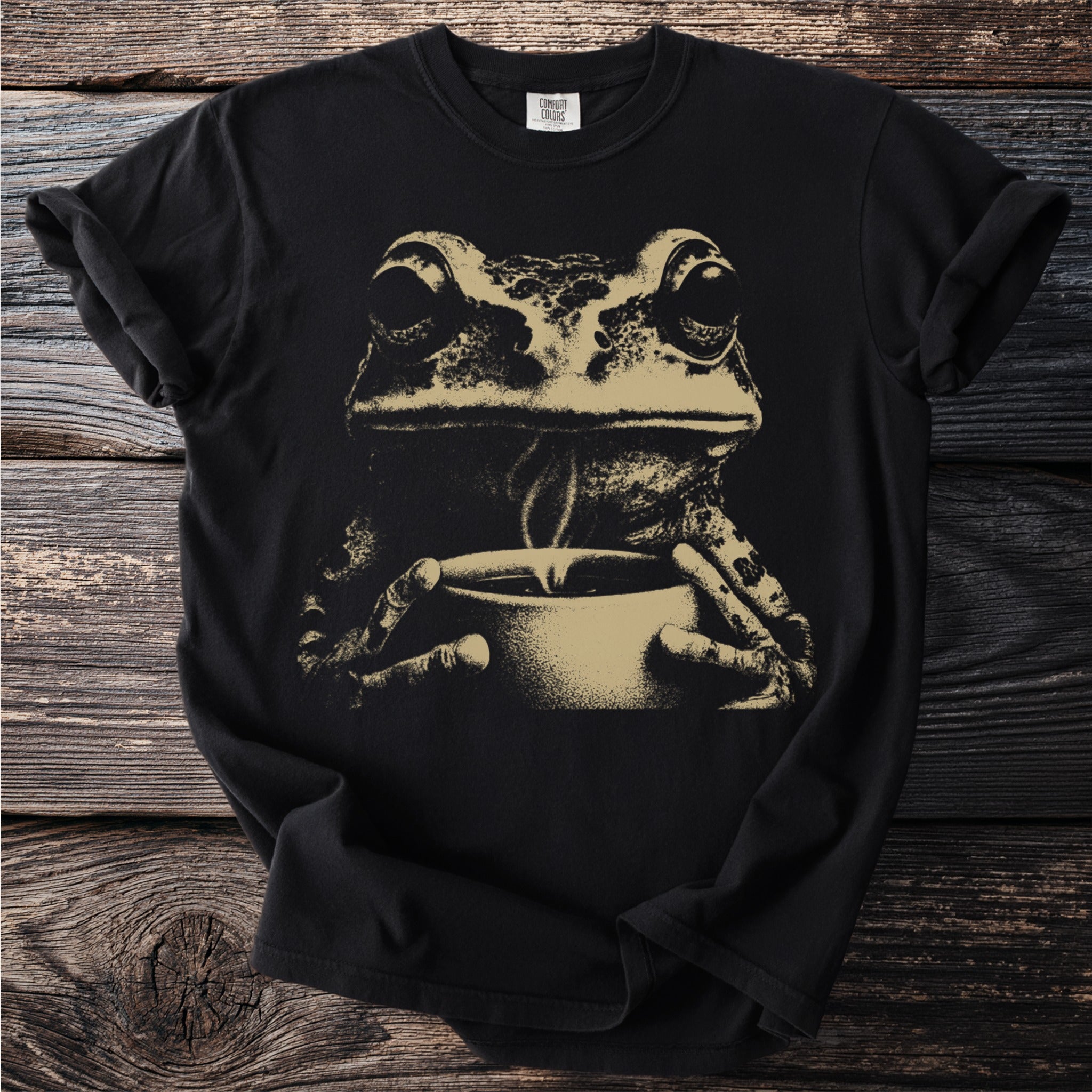 Black t-shirt with a sepia tone print of a frog holding a steaming cup.