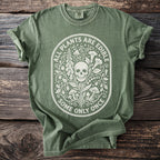 Green t-shirt with white oval graphic featuring a skull, plants, mushrooms, and text "ALL PLANTS ARE EDIBLE SOME ONLY ONCE".