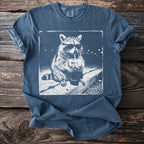 Blue t-shirt with white graphic of a raccoon in sunglasses drinking a beverage.