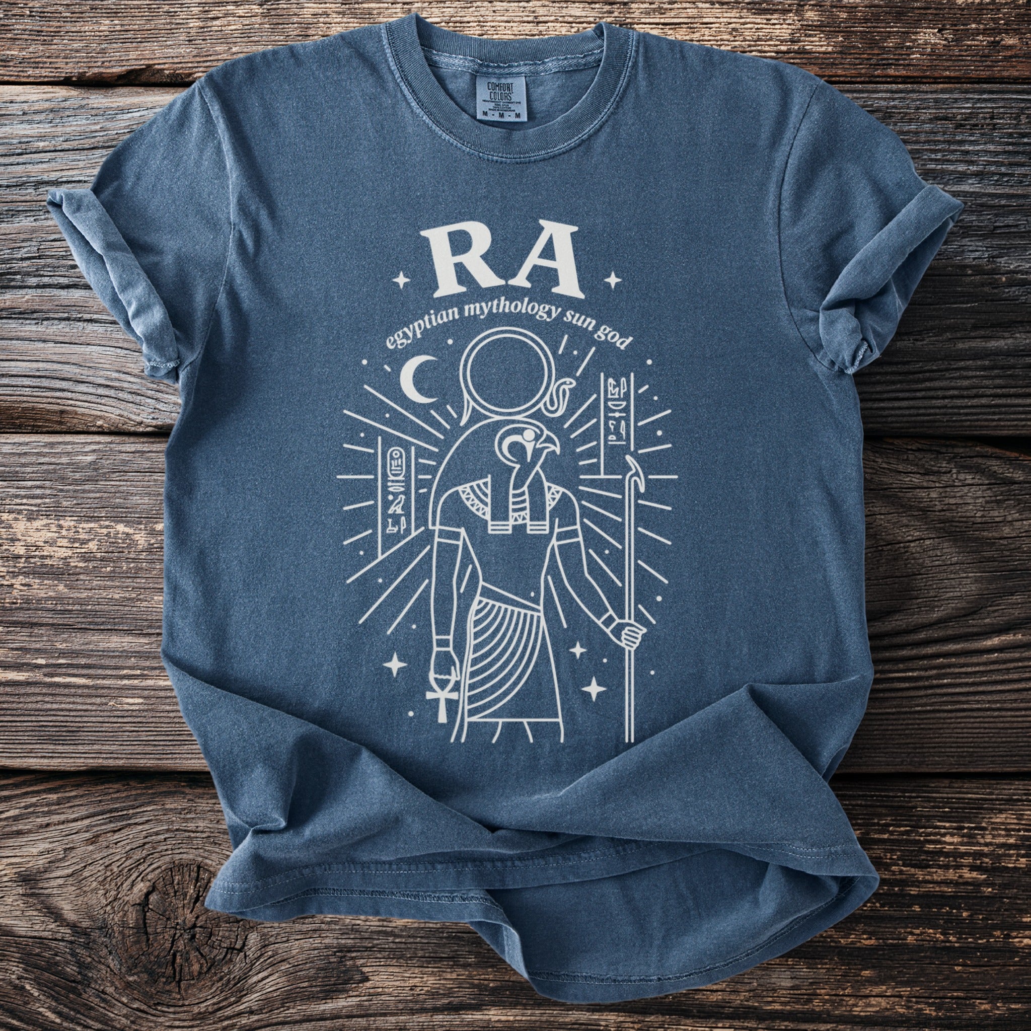 Blue t-shirt with graphic of Egyptian sun god Ra and hieroglyphics.
