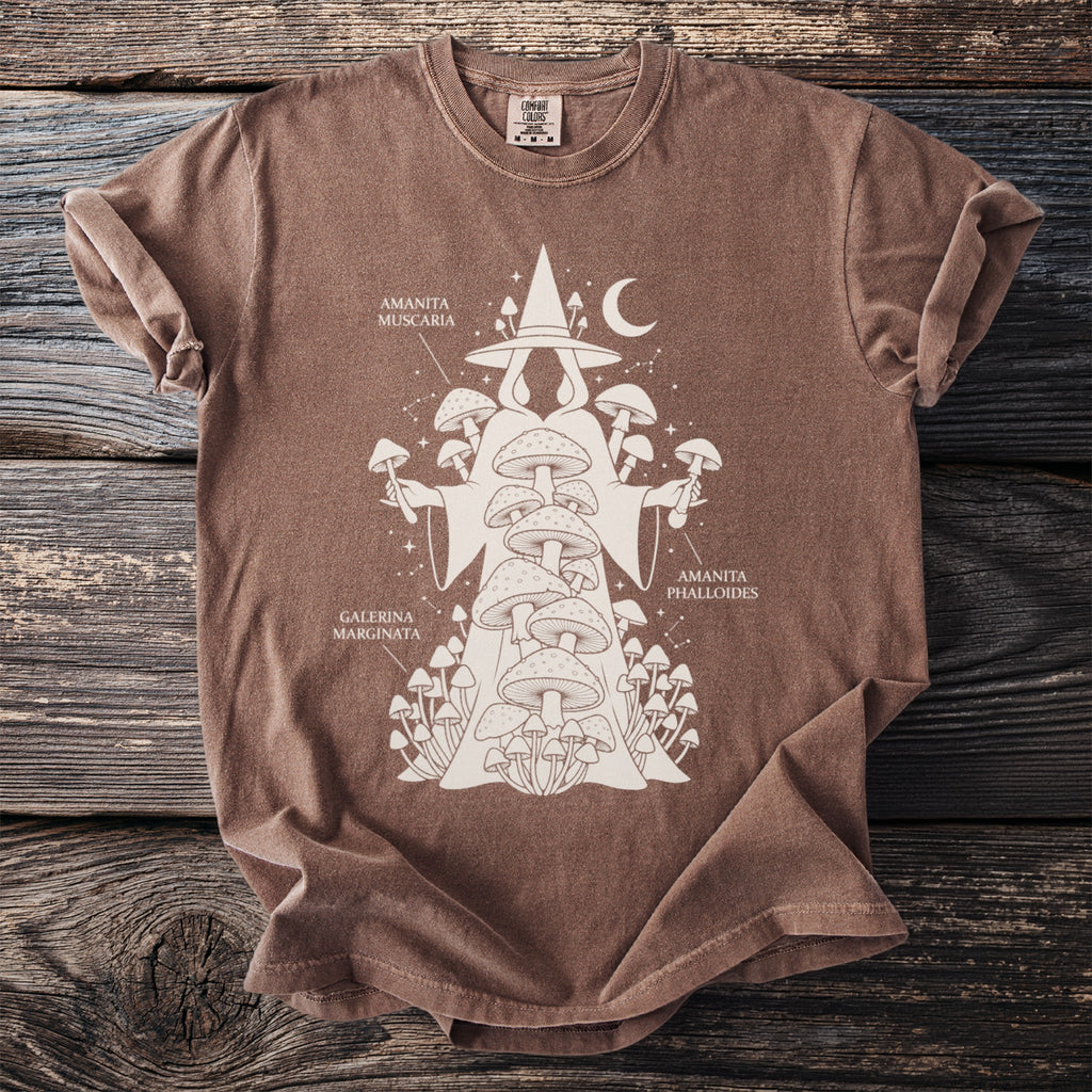 Brown t-shirt with a cream illustration of a robed figure adorned with mushrooms and celestial elements.
