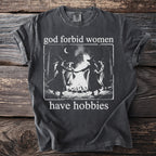 Dark grey t-shirt with witches dancing around a bonfire and text "god forbid women have hobbies".