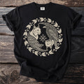 Black t-shirt with a circular cream design of a lynx and raven surrounding a snowflake.