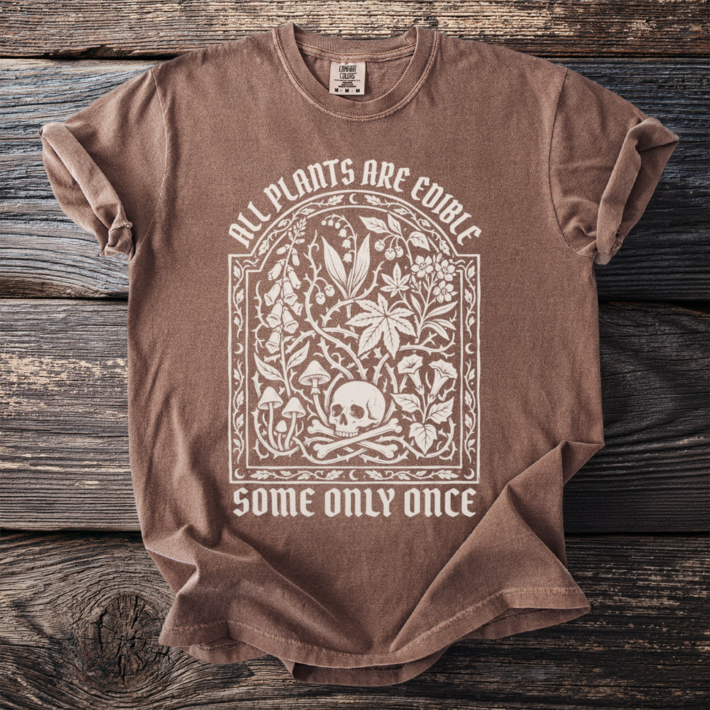 Brown t-shirt with white text and skull graphic: "All plants are edible, some only once."
