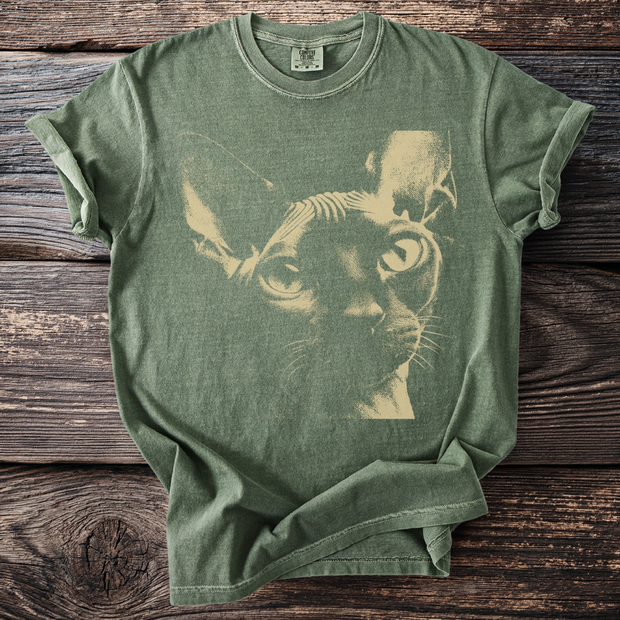 Green t-shirt with a light beige Sphinx cat illustration centered on the front.