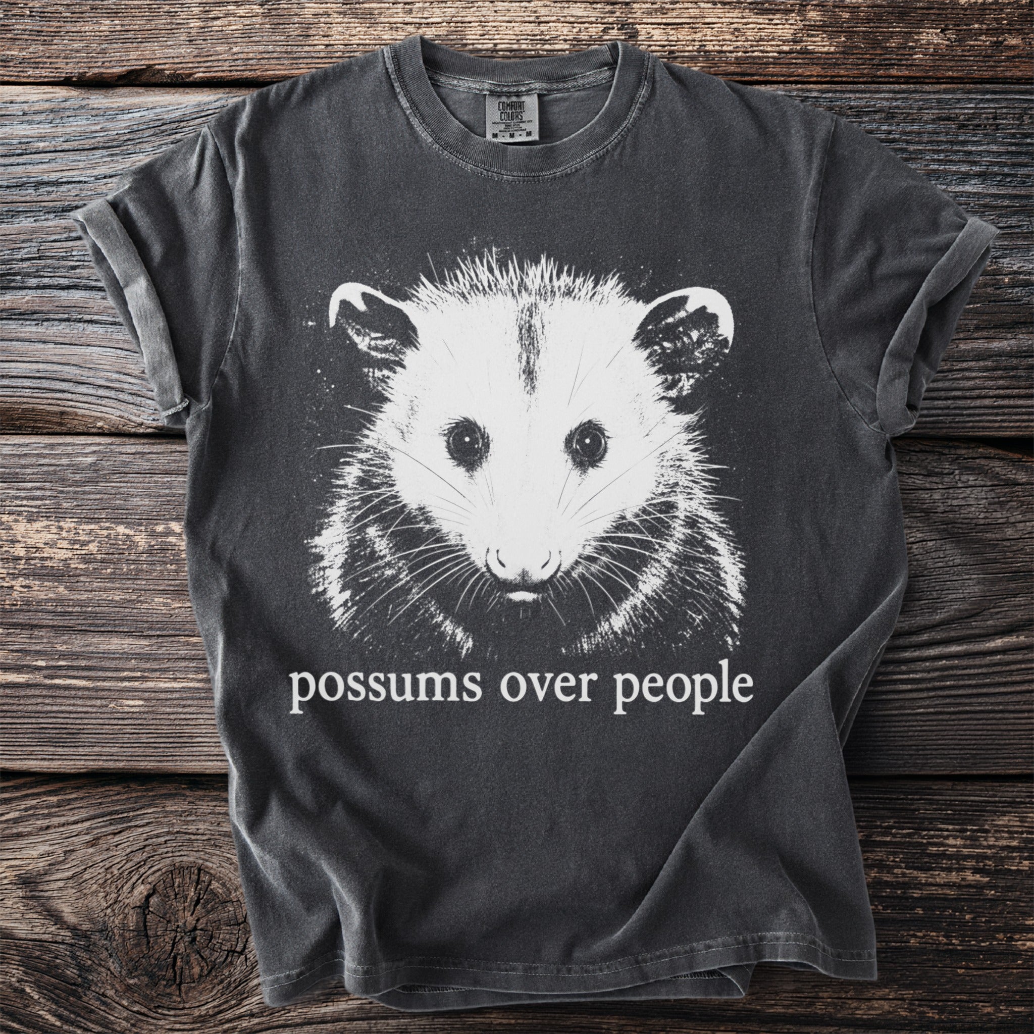 Charcoal t-shirt with a white graphic of an opossum and text "possums over people".