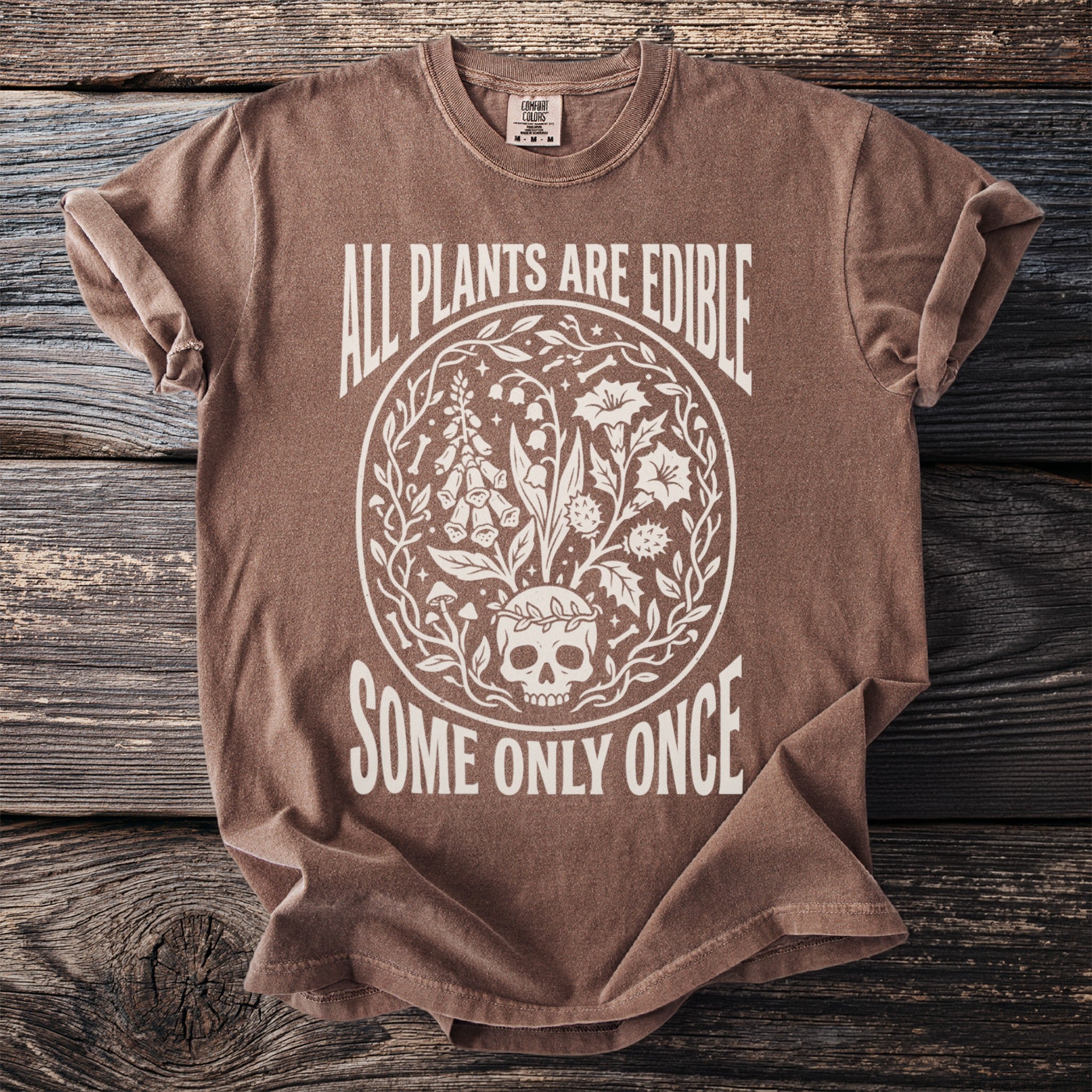 Brown t-shirt with white text and graphic including skull and plants.