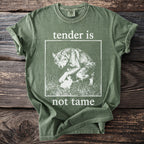 Green t-shirt with wolf and rabbit graphic and text "tender is not tame".