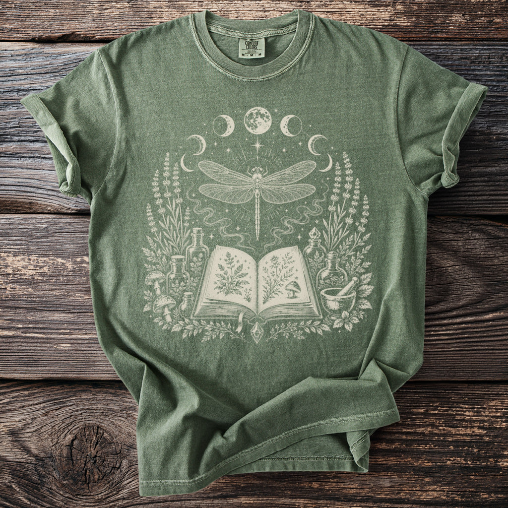 Green t-shirt with a celestial dragonfly, open book, and botanical illustrations.