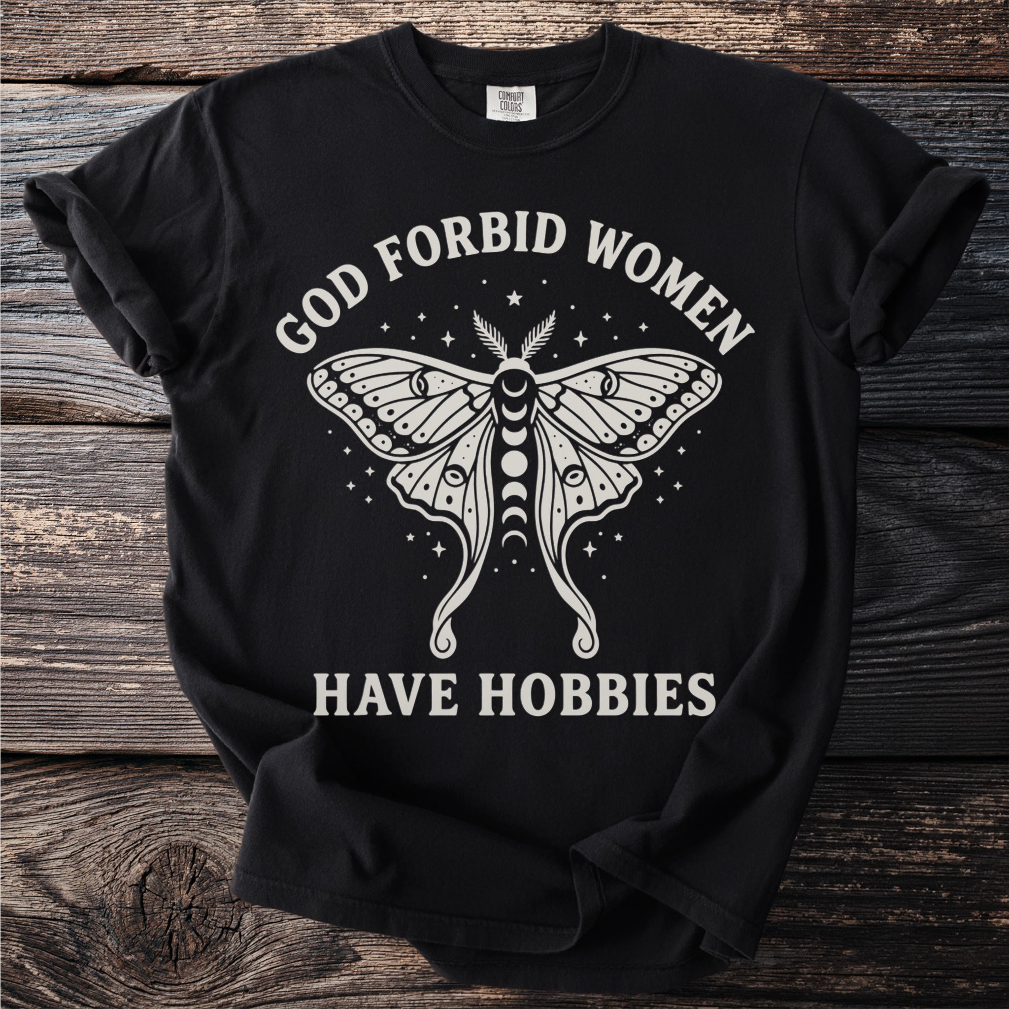 Black t-shirt with a moth graphic and text "GOD FORBID WOMEN HAVE HOBBIES".