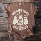 Brown t-shirt with "God forbid women have hobbies" graphic featuring three ghosts.