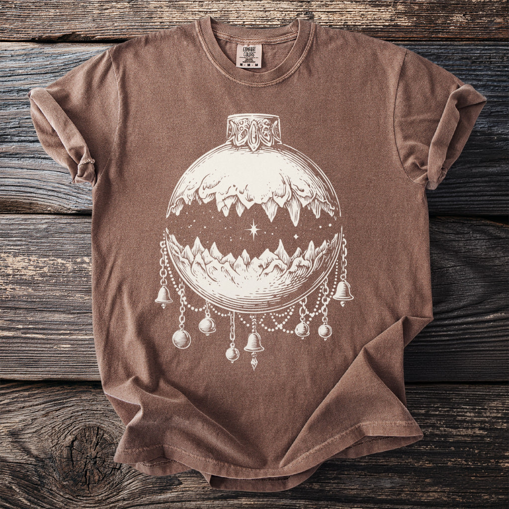 Brown t-shirt with cream line art of a mountain landscape inside an ornament.