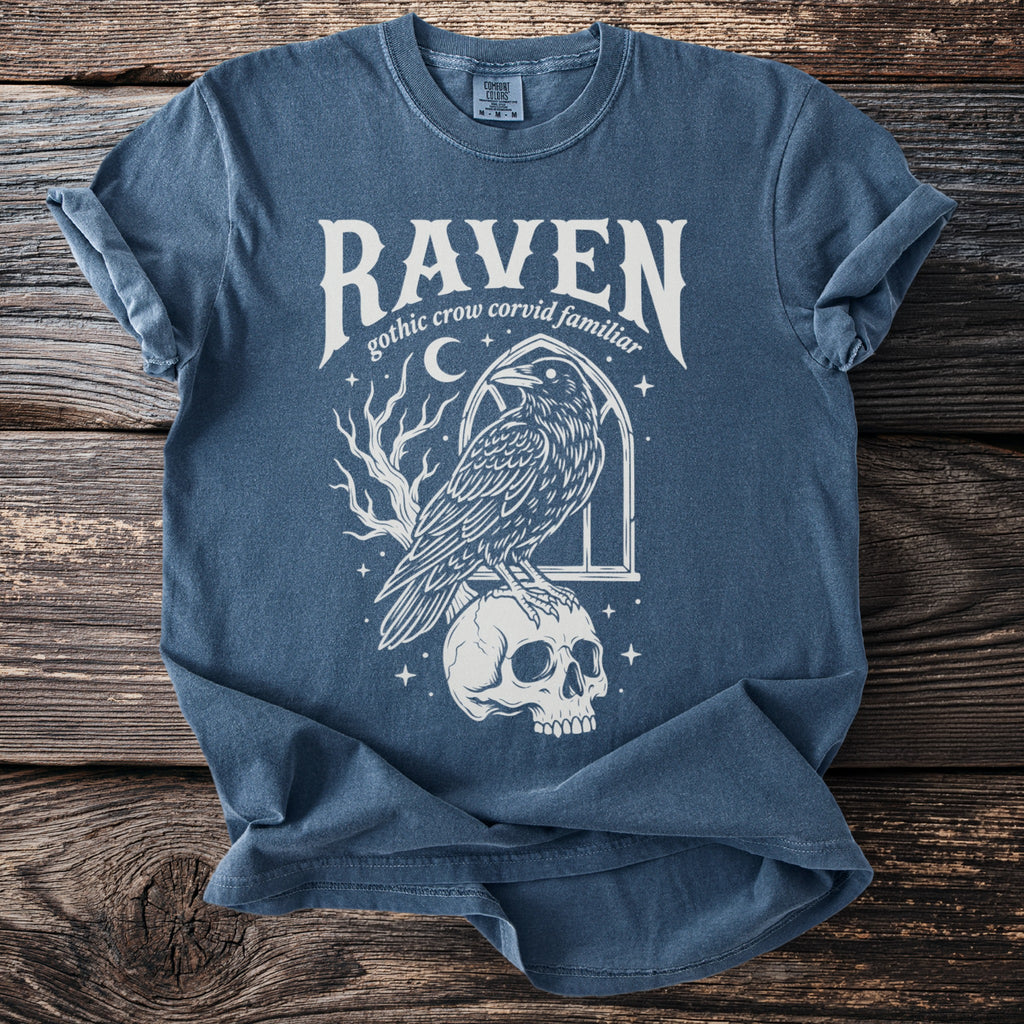 T-shirt with white graphic of a raven on a skull, reading "Raven gothic crow corvid familiar".