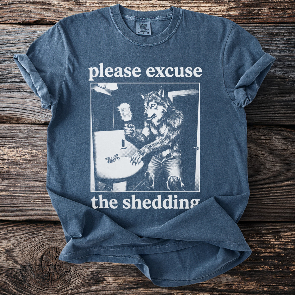 T-shirt with graphic of werewolf at sink, text "please excuse the shedding."