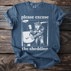 T-shirt with graphic of werewolf at sink, text "please excuse the shedding."