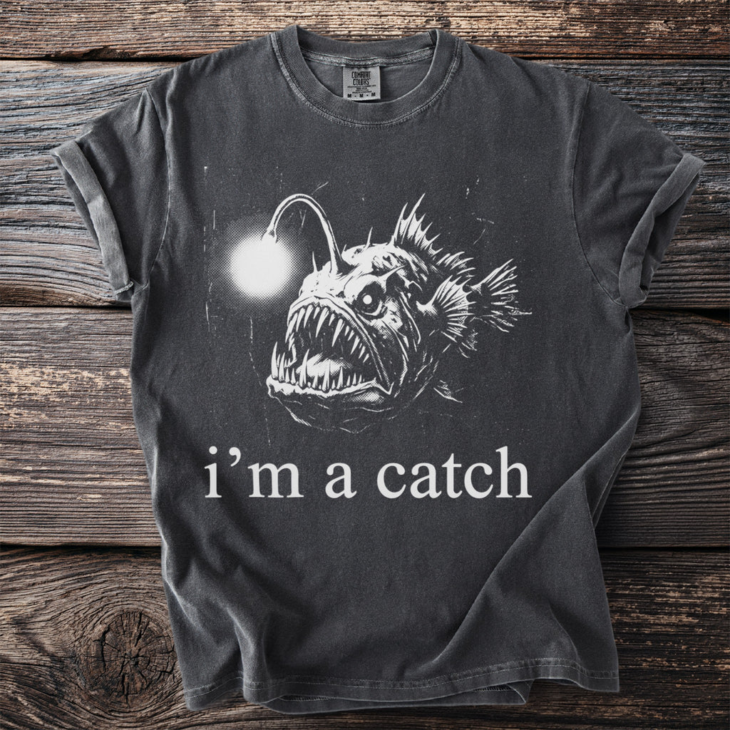 Dark t-shirt with large front graphic of an anglerfish and text "i'm a catch".