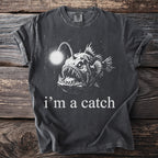 Dark t-shirt with large front graphic of an anglerfish and text "i'm a catch".