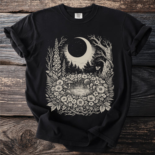 Black t-shirt with a detailed moonlit forest and floral scene illustration.