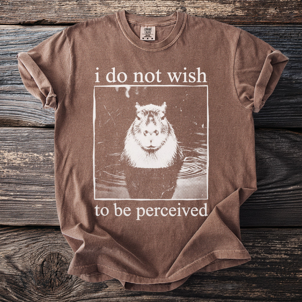 Brown t-shirt with a capybara in water and text "i do not wish to be perceived".