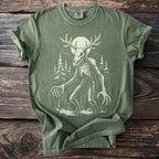 Green t-shirt with a distressed print of a skeletal creature with antlers in a forest.