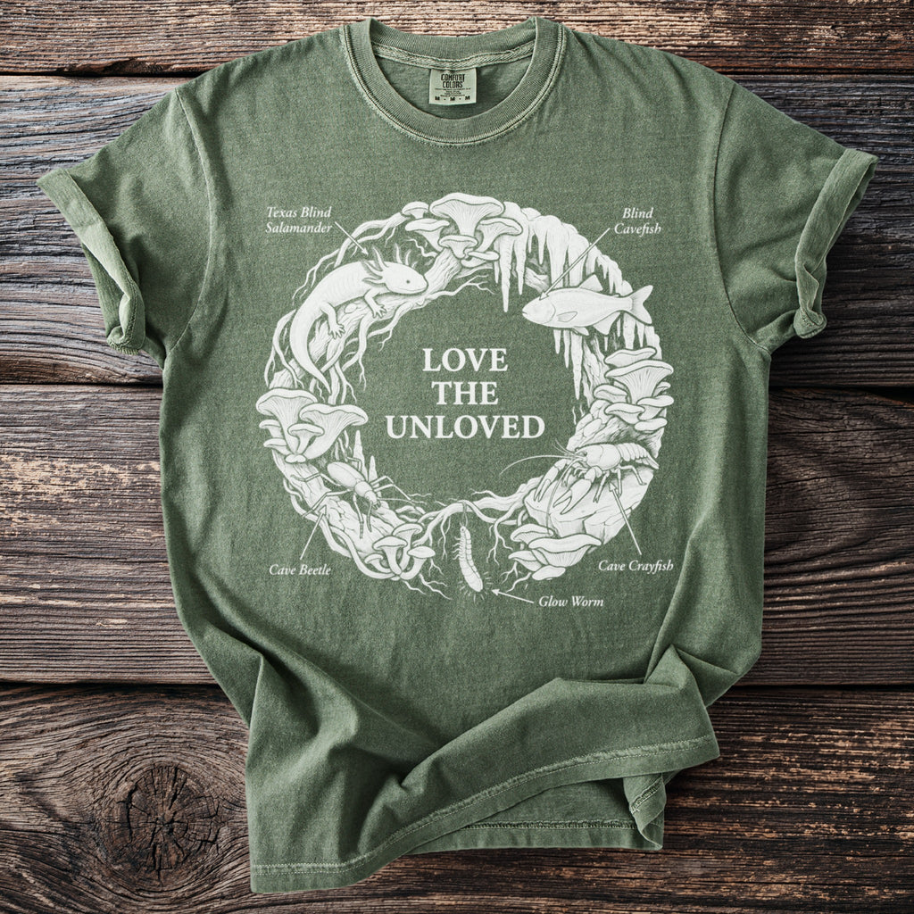 Green t-shirt with white "Love the Unloved" text and cave creatures in a circle.