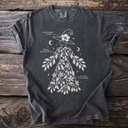 Dark t-shirt features a white outline of a witch adorned with foliage labeled Hyoscyamus Niger, Atropa Belladonna, Solanum Dulcamara.