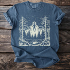 Blue t-shirt with a white graphic of an alien figure floating over a forest at night.