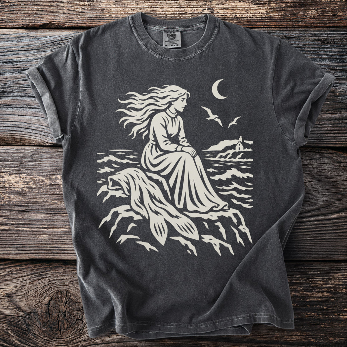 T-shirt with cream graphic of woman with flowing hair by lighthouse under moon