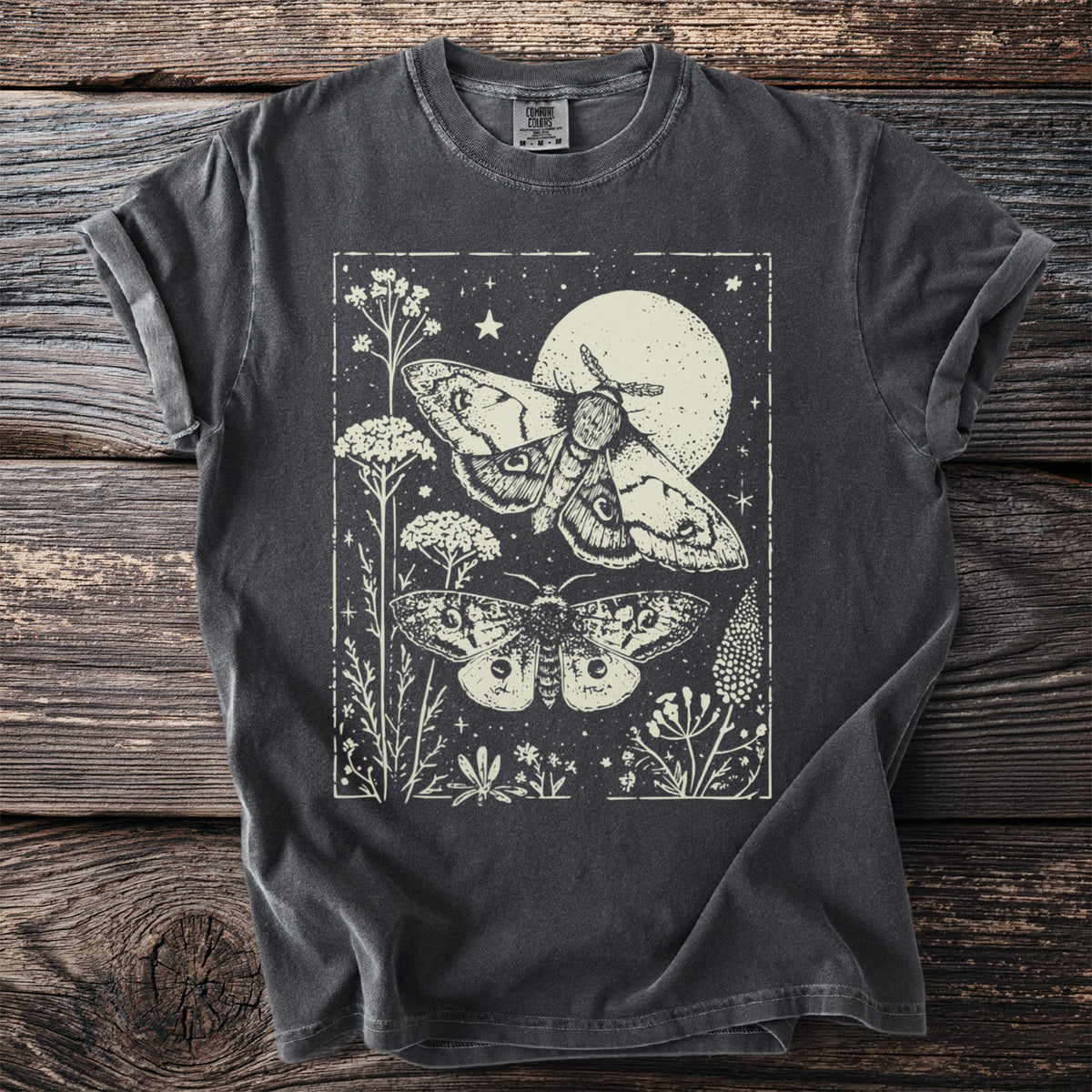 Dark grey t-shirt with a light cream graphic of two moths, a moon, and plants.