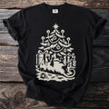 Black t-shirt with a cream folk-cut print: an opossum lies on its back under a candlelit Christmas tree, playing dead among the presents.
