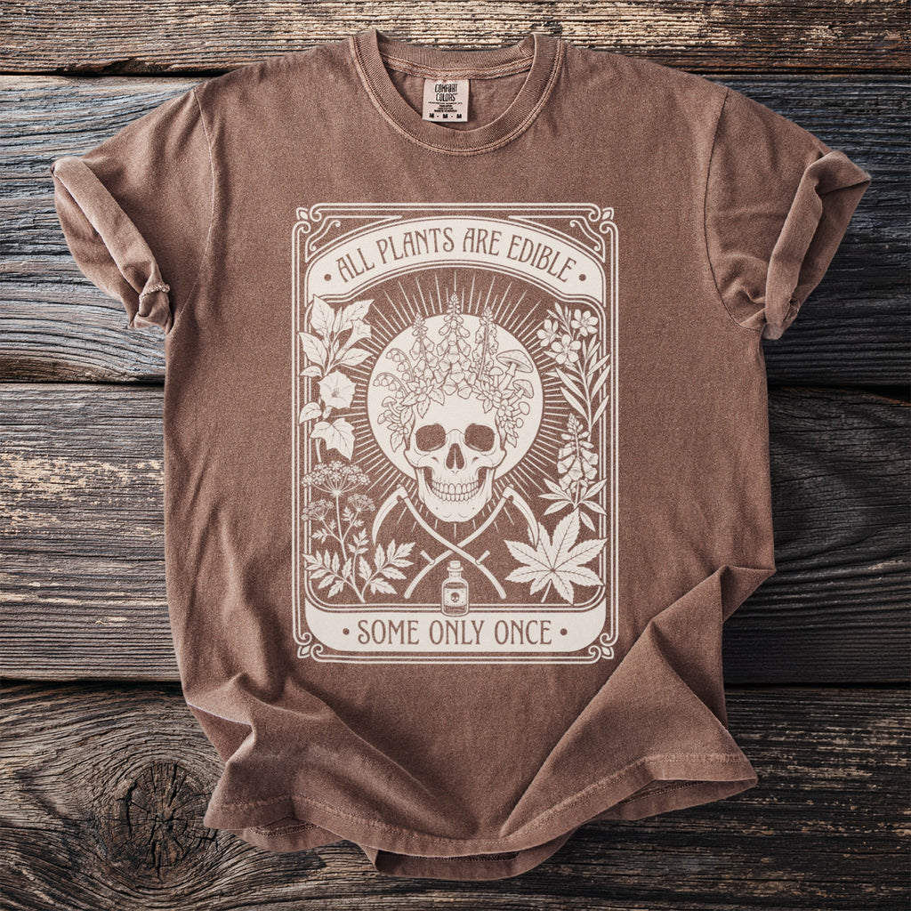 Brown t-shirt with white graphic of skull, plants, and text: ALL PLANTS ARE EDIBLE. SOME ONLY ONCE.