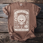 Brown t-shirt with white graphic of skull, plants, and text: ALL PLANTS ARE EDIBLE. SOME ONLY ONCE.