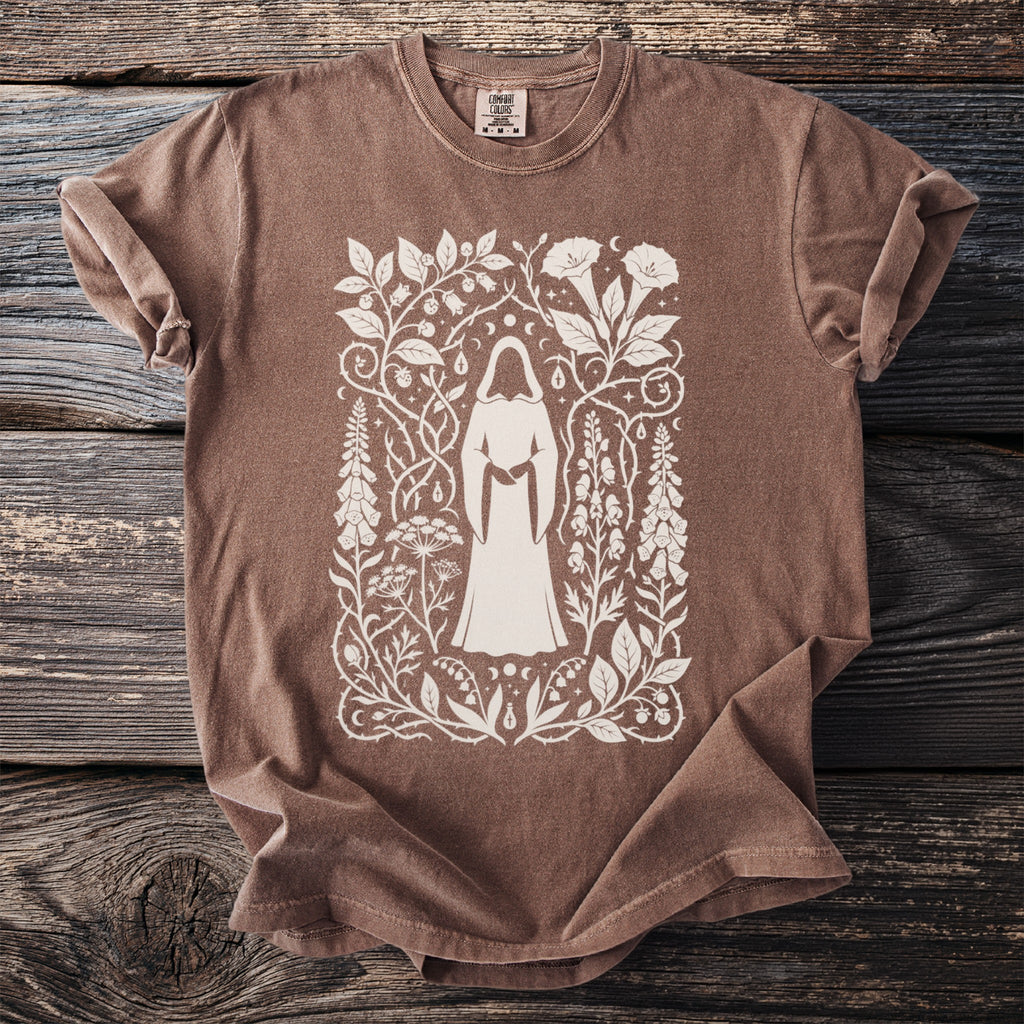 Brown t-shirt with white graphic of hooded figure and botanical elements.