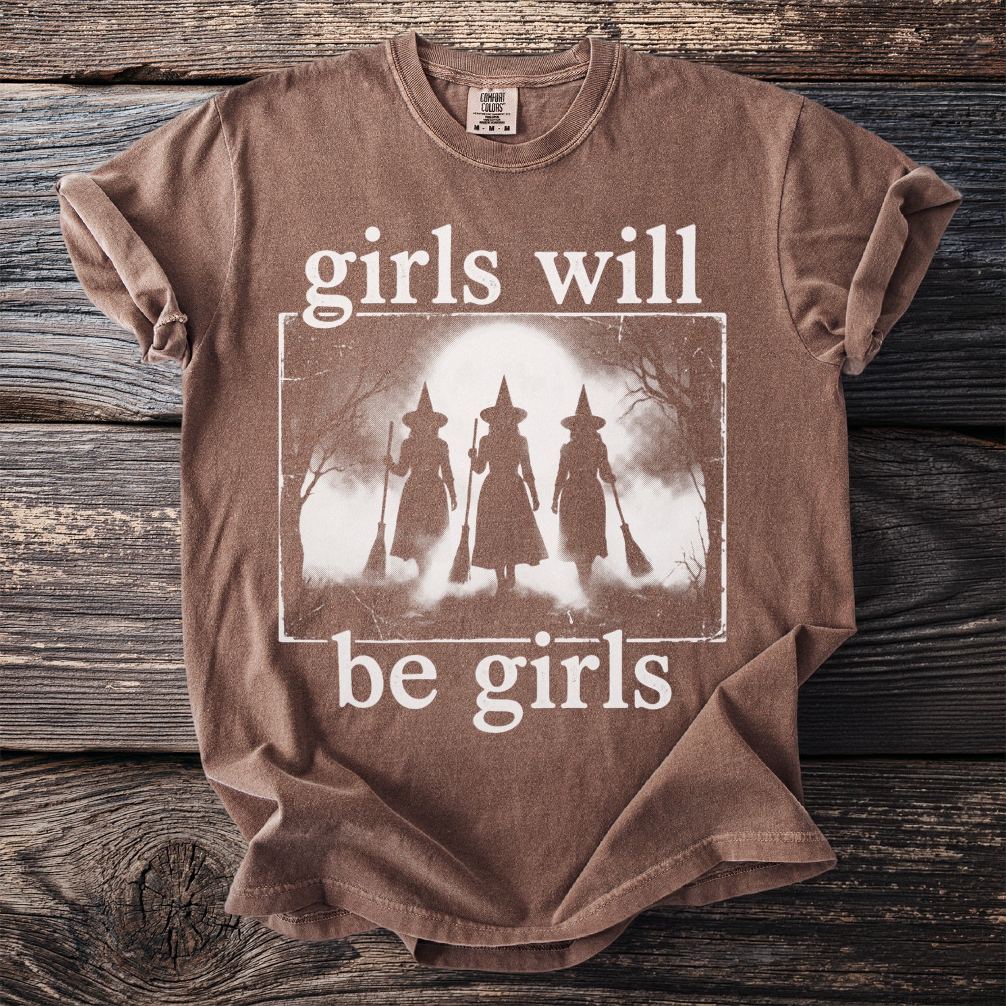 Brown t-shirt with "girls will be girls" text and three witch silhouettes.