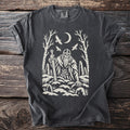 Dark t-shirt with a cream graphic of a viking, sword, moon, birds, and trees.