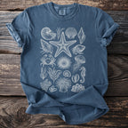 Blue t-shirt with a white vintage-style marine life print including shells, starfish, and a seahorse.