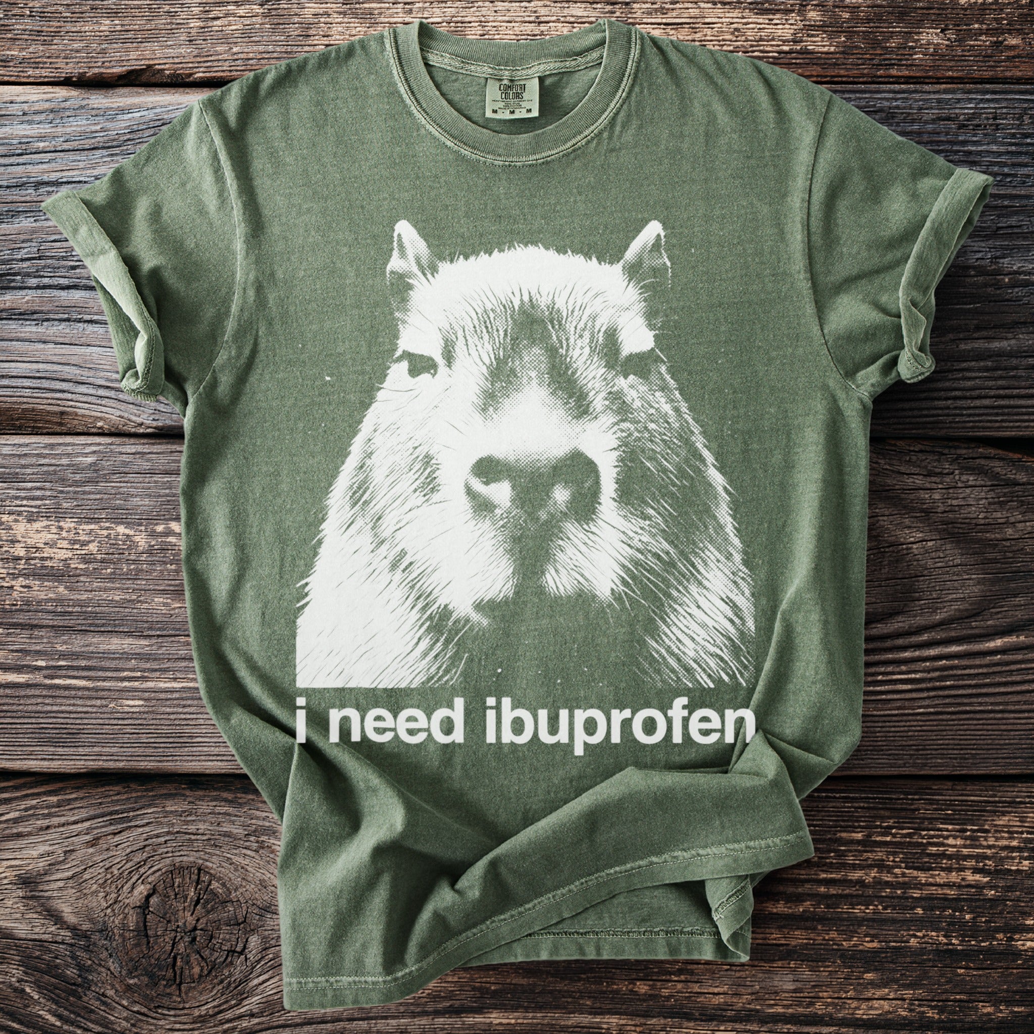 Green t-shirt with distressed white capybara graphic and text "i need ibuprofen".
