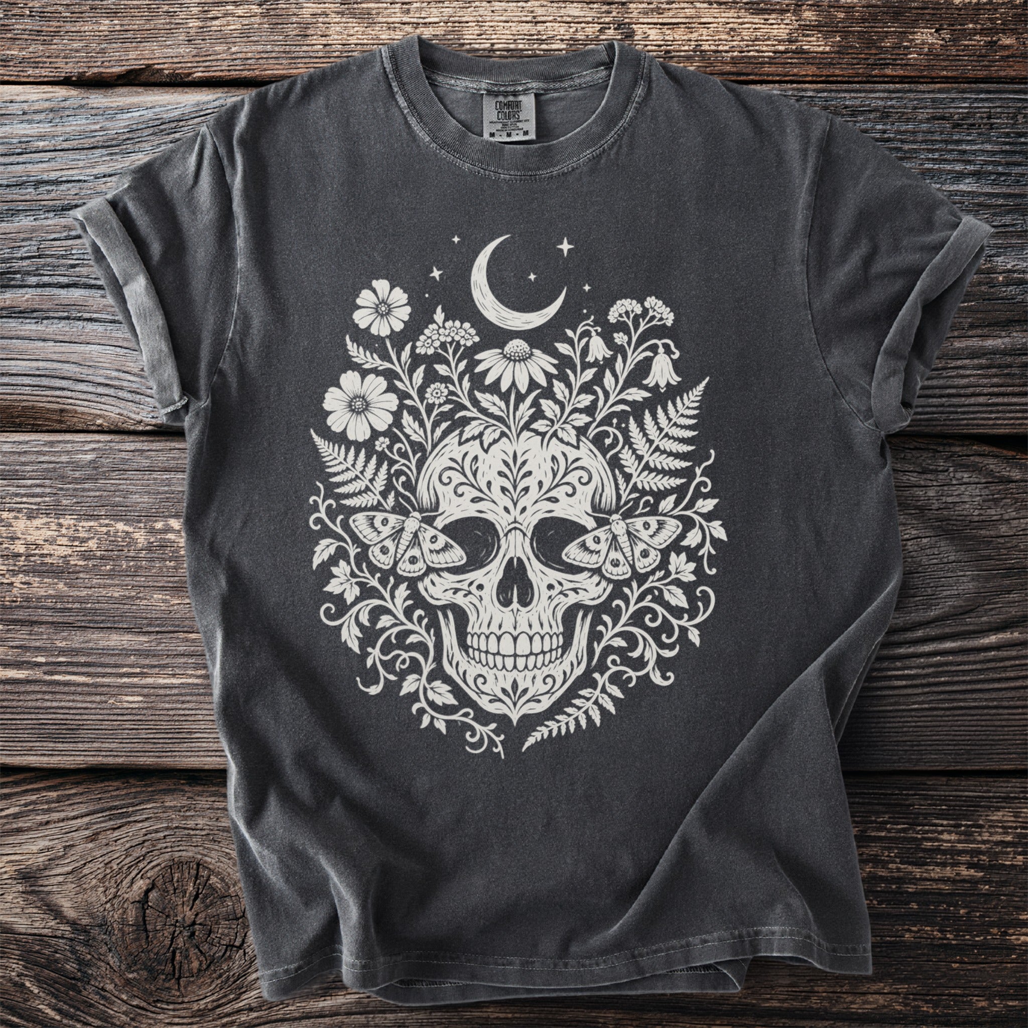 Dark t-shirt with cream skull, moth, crescent moon, and floral design.