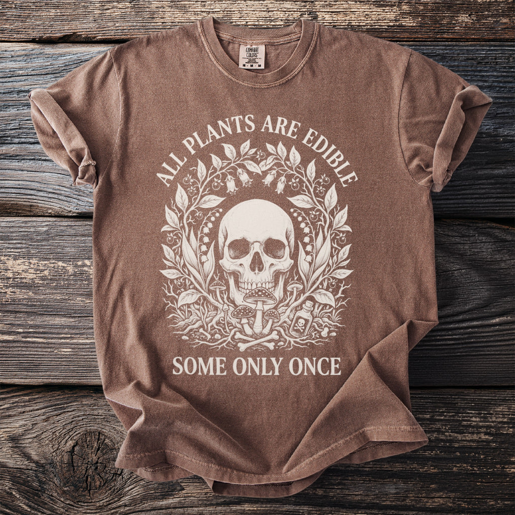 Brown t-shirt with a skull, plants, mushrooms, and bones graphic and text.