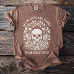 Brown t-shirt with a skull, plants, mushrooms, and bones graphic and text.