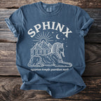 Blue t-shirt with white graphic featuring a sphinx, pyramids, sun, moon, and stars.