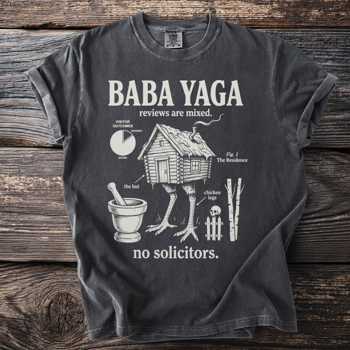 T-shirt with "Baba Yaga reviews are mixed" and illustrations of her hut on chicken legs.
