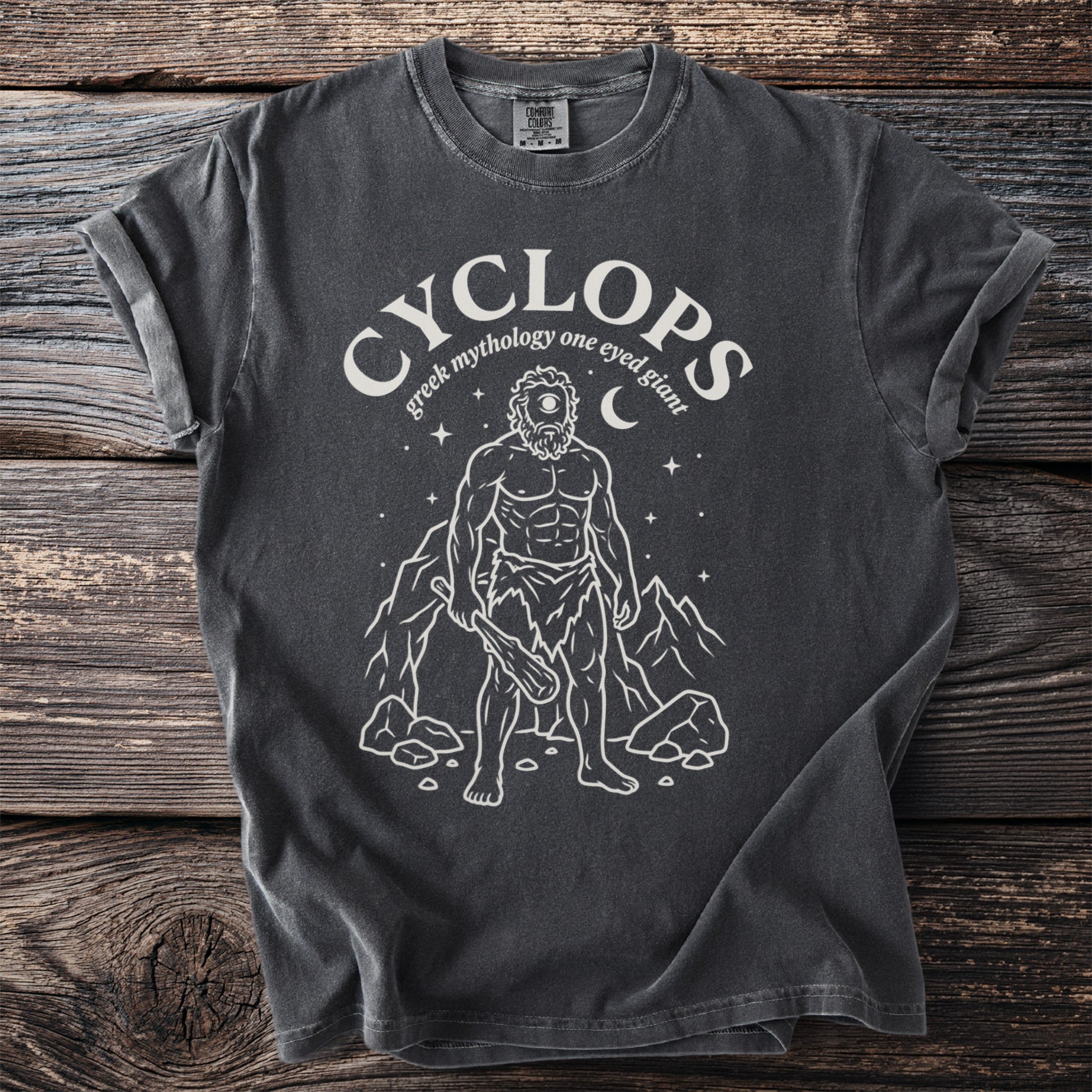 Dark t-shirt with white graphic of a cyclops and text "cyclops greek mythology one eyed giant".