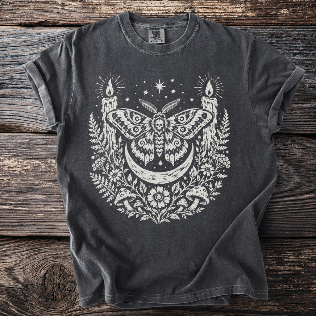 Dark t-shirt with a moth, crescent moon, candles, and floral design.